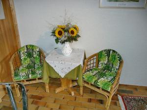 einen Tisch mit 2 Stühlen und eine Vase mit Sonnenblumen in der Unterkunft Gästehaus Heller in Elmstein