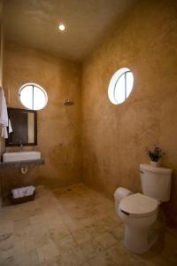 a bathroom with a toilet and a sink and two windows at Hotel Boutique SAYAB in Valladolid