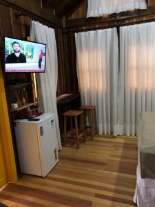 uma sala de estar com uma televisão e um frigorífico em CASA DI PECORA - POUSADA RURAL em Lauro Müller