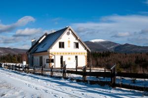 ein weißes Haus mit schwarzem Dach im Schnee in der Unterkunft Gościniec Horb in Wetlina