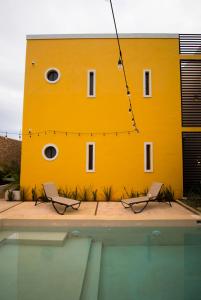 un bâtiment jaune avec deux chaises à côté d'une piscine dans l'établissement Hotel Boutique SAYAB, à Valladolid