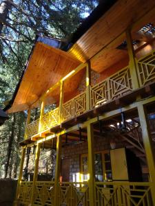 a house with a wrap around deck in the woods at The Hosteller Manali in Manāli