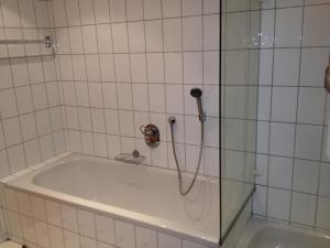 e bagno piastrellato con vasca e doccia. di Gästehaus Stapf a Oberaurach