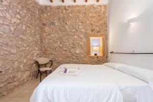 a bedroom with a white bed and a stone wall at Petit Hotel Hostatgeria La Victoria in Alcudia