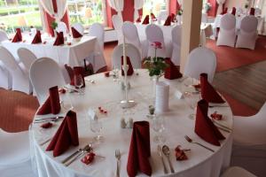a dining room with white tables and chairs with red napkins at Im Wiesengrund in Lalendorf