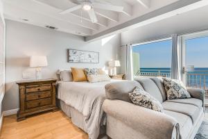 a bedroom with a bed and a couch and a window at Big O Beach - White Sands Townhomes in Pensacola Beach