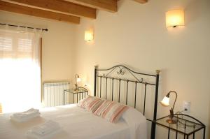 a bedroom with a bed with white sheets and a window at Casa con piscina y vistas a montaña - Cal Solsona in La Baronia de Rialb