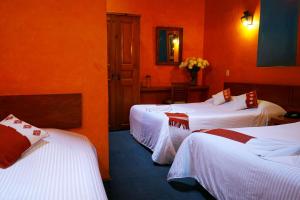 two beds in a room with orange walls at Hotel Posada El Paraíso in San Cristóbal de Las Casas