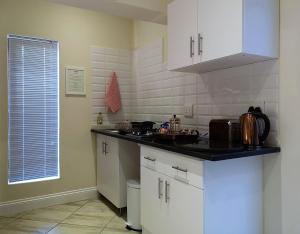 a kitchen with white cabinets and a black counter top at Andante Lodge in Pretoria