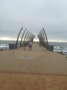 a group of people walking on a pier near the ocean at Somerset Inn in Durban