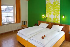 1 dormitorio con 1 cama grande y pared verde en Stadtcafé Hotel garni, en Hammelburg