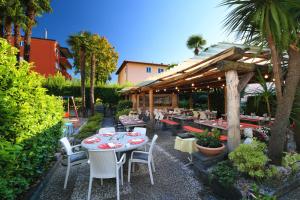 a patio with tables and chairs in a garden at Osteria Ticino by Ketty & Tommy in Ascona