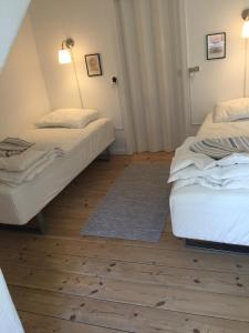 two beds in a room with wooden floors at Nakskov Overnatning in Nakskov
