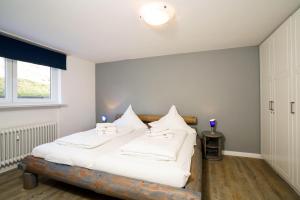 um quarto com uma cama com lençóis brancos e almofadas em Haus-Carola-App-11-Sylter-Seestern em Wenningstedt