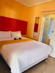 a bedroom with a large bed with a red headboard at Maite Villa Lodge in Thohoyandou