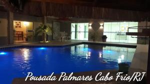 a large swimming pool with blue lights in a house at Pousada Palmares in Cabo Frio
