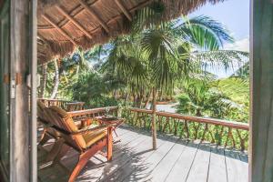 a porch with a chair and palm trees at Villa Pescadores Tulum in Tulum