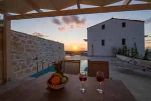 a table with a basket of fruit and two glasses of wine at Petras Resort in Falasarna