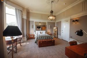 une chambre avec un lit, un bureau et une lampe dans l'établissement Cornhill Castle, à Biggar