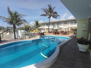 a pool at a resort with palm trees and a building at Hotel Portal Do Mar in Conde