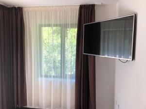 a flat screen tv in a room with a window at Pensiunea Julian House in Moieciu de Jos