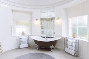 a bath tub in a white bathroom with windows at Cornhill Castle in Biggar