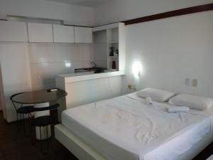 sypialnia z białym łóżkiem i małym stołem w obiekcie Tabajara Flats Praia de Iracema w mieście Fortaleza +30 zdjęć
