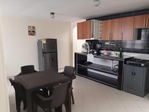cocina con mesa y nevera negra en Apartamentos Turisticos EL ZIPA en Zipaquirá
