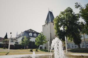 a fountain in front of a building with a tower at Penzion U Johanky in Kadaň