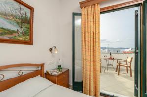 a bedroom with a bed and a balcony with a table at Dolphin Studios in Agia Anna Naxos