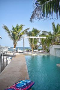 a swimming pool next to a beach with palm trees at Posada Lamar Tulum Beach Front and Pool in Tulum