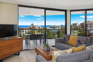 ein Wohnzimmer mit einem TV, einem Sofa und einem Tisch in der Unterkunft Mariners Resort Kings Beach in Caloundra