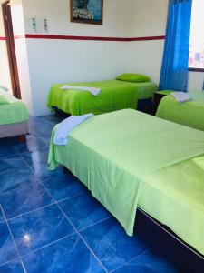 Habitación con 3 camas con colchas verdes. en Posada del Caminante, en Puerto Villamil