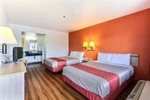 Habitación de hotel con 2 camas y pared de color naranja en Coastal Valley Inn, en Castroville