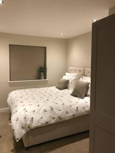 a bedroom with a large bed with a white comforter at Northdown Lodge - Stunning property on the Kent Northdowns in Hollingbourne