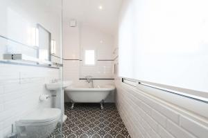 un bagno bianco con vasca, WC e lavandino di Résidence du Louvre a Parigi Altre 20 foto