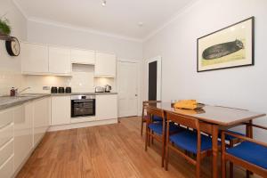 a kitchen with white cabinets and a wooden table and chairs at 16 1 Eildon Street in Edinburgh