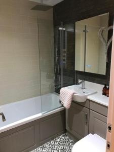 La salle de bains est pourvue d'une baignoire, d'un lavabo et d'une douche. dans l'établissement Northdown Lodge - Stunning property on the Kent Northdowns, à Hollingbourne