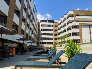 a patio with blue chairs and tables and buildings at Gold Flat - Praia do Cabo Branco in João Pessoa