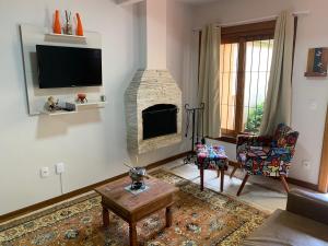 a living room with a fireplace and a tv at Chalé aconchegante para família no Centro in Penedo