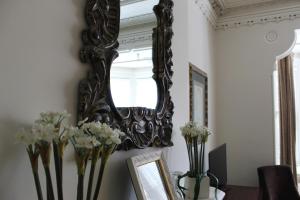 a mirror hanging on a wall with vases of flowers at Norfolk Guest House Inn in Guelph