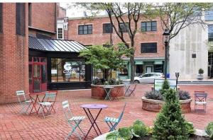 a brick courtyard with chairs and tables in front of a building at New Haven Stays in New Haven
