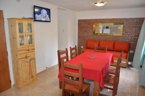 a dining room with a red table and a couch at C&W Vacaciones Diferentes in Villa Carlos Paz
