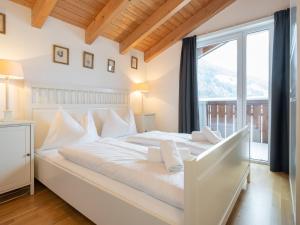 Cama blanca en habitación con ventana grande en Holiday home in Mittersill near ski area, en Mittersill