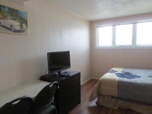 a bedroom with a bed and a tv and chairs at College Park Bed & Breakfast in Saskatoon