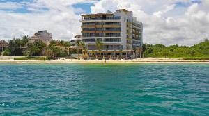 a large building on a beach next to the water at The Fives Oceanfront in Puerto Morelos