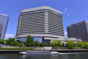 a boat in a river in front of a building at Hotel New Otani Osaka in Osaka