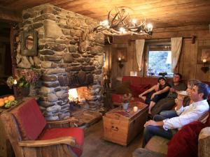 un grupo de personas sentadas en una sala de estar con chimenea de piedra en Luxurious Chalet with Jacuzzi and Sauna en Waimes