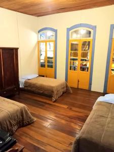een kamer met 2 bedden, 2 ramen en houten vloeren bij Casa Colonial in Ouro Preto