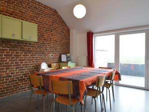 een eettafel met stoelen en een bakstenen muur bij Cottage in Clavier Station with infrared sauna in Modave